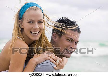 Man giving woman piggyback ride on the beach View Large Photo Image Stock Image - Man giving woman piggyback ride on the beach. Fotosearch
