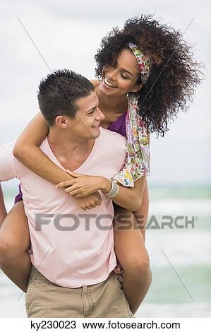 Man giving woman piggyback ride on the beach View Large Photo Image Stock Image - Man giving woman piggyback ride on the beach. Fotosearch