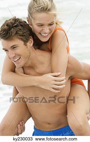 Man giving woman piggyback ride on the beach View Large Photo Image Stock Image - Man giving woman piggyback ride on the beach. Fotosearch
