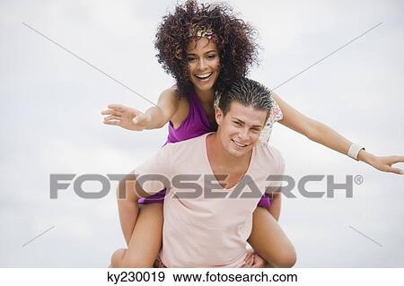 Man giving woman piggyback ride on the beach View Large Photo Image Stock Photo - Man giving woman piggyback ride on the beach. Fotosearch