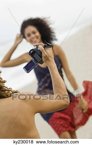 Man making a video of a woman on the beach View Large Photo Image Stock Photo - Man making a video of a woman on the beach. Fotosearch