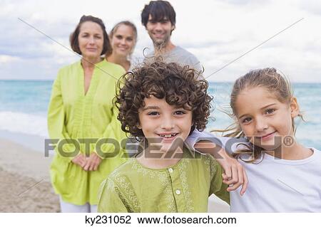Boy and a girl smiling with their family behind them on the beach View Large Photo Image Stock Image - Boy and a girl smiling with their family behind them on the beach. Fotosearch