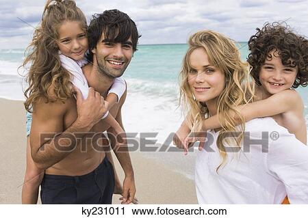 Couple giving piggyback ride to their children on the beach View Large Photo Image Stock Image - Couple giving piggyback ride to their children on the beach. Fotosearch