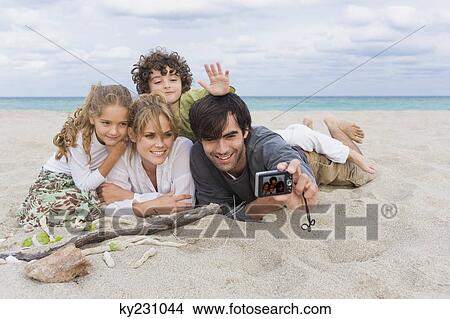 Man taking a picture of his family with a digital camera on the beach View Large Photo Image Picture - Man taking a picture of his family with a digital camera on the beach. Fotosearch