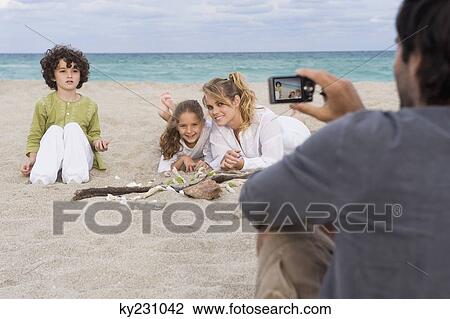 Man taking a picture of his family with a digital camera on the beach View Large Photo Image Stock Image - Man taking a picture of his family with a digital camera on the beach. Fotosearch