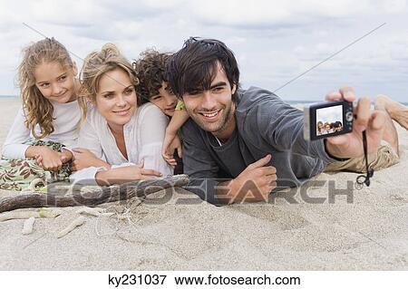 Man taking a picture of his family with a digital camera on the beach View Large Photo Image Stock Photo - Man taking a picture of his family with a digital camera on the beach. Fotosearch