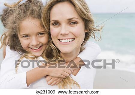 Woman giving her daughter piggyback on the beach View Large Photo Image Stock Photo - Woman giving her daughter piggyback on the beach. Fotosearch