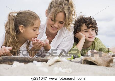 Woman lying with her children on the beach View Large Photo Image Stock Photo - Woman lying with her children on the beach. Fotosearch
