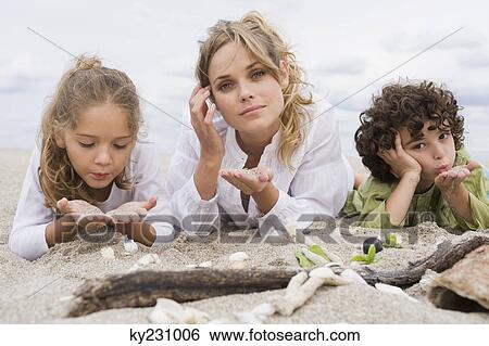 Woman lying with her children on the beach View Large Photo Image Stock Photograph - Woman lying with her children on the beach. Fotosearch