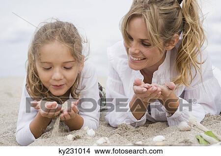 Woman lying with her daughter on the beach View Large Photo Image Picture - Woman lying with her daughter on the beach. Fotosearch