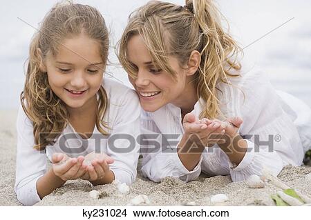 Picture - Woman lying with her daughter on the beach. Fotosearch