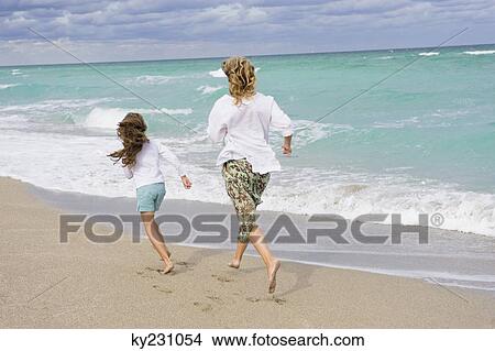 Picture - Woman running with her daughter on the beach. Fotosearch