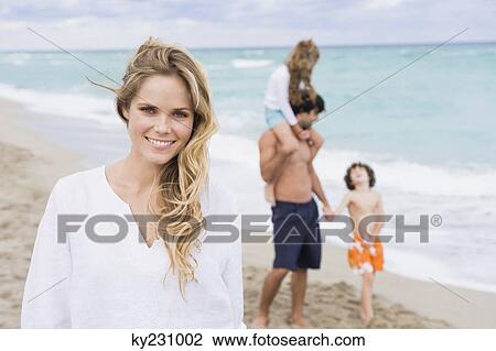 Woman smiling with her family in the background View Large Photo Image Stock Image - Woman smiling with her family in the background. Fotosearch
