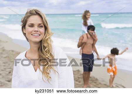 Woman smiling with her family in the background View Large Photo Image Stock Image - Woman smiling with her family in the background. Fotosearch