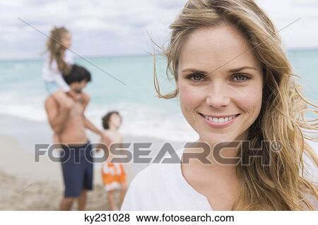 Stock Photo - Woman smiling with her family in the background. Fotosearch