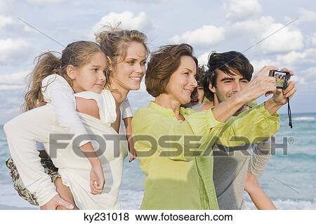 Woman taking a picture of her family with a digital camera View Large Photo Image Stock Photo - Woman taking a picture of her family with a digital camera. Fotosearch