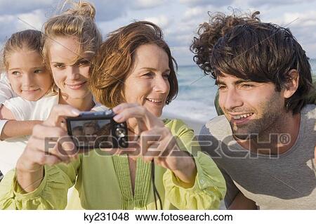 Woman taking a picture of her family with a digital camera View Large Photo Image Stock Photo - Woman taking a picture of her family with a digital camera. Fotosearch