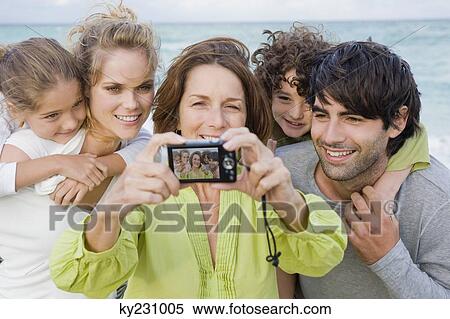 Stock Photography - Woman taking a picture of her family with a digital camera. Fotosearch