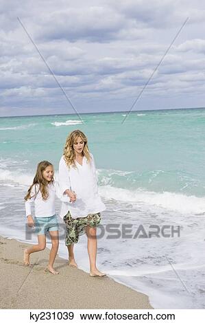 Woman walking on the beach with her daughter View Large Photo Image Stock Photo - Woman walking on the beach with her daughter. Fotosearch