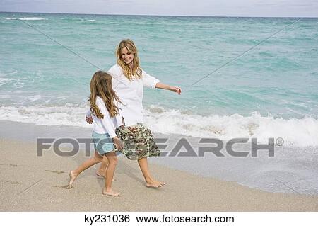 Woman walking on the beach with her daughter View Large Photo Image Stock Photograph - Woman walking on the beach with her daughter. Fotosearch