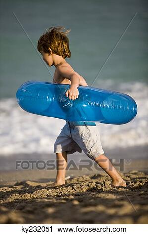Boy carrying an inflatable ring on the beach View Large Photo Image Stock Image - Boy carrying an inflatable ring on the beach. Fotosearch