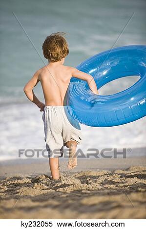 Boy carrying an inflatable ring on the beach View Large Photo Image Stock Photography - Boy carrying an inflatable ring on the beach. Fotosearch
