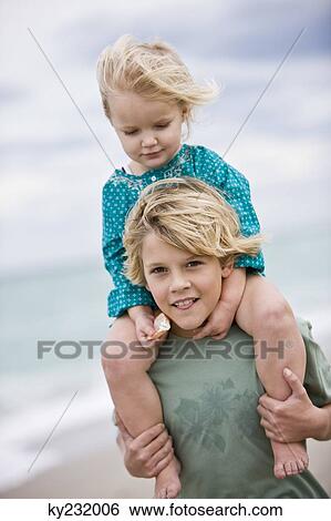 Boy carrying his sister on shoulders on the beach View Large Photo Image Stock Photograph - Boy carrying his sister on shoulders on the beach. Fotosearch