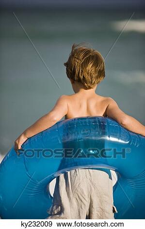 Boy holding an inflatable ring on the beach View Large Photo Image Stock Photo - Boy holding an inflatable ring on the beach. Fotosearch