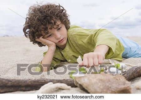 Boy playing with sand on the beach View Large Photo Image Stock Image - Boy playing with sand on the beach. Fotosearch