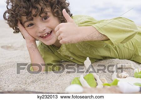 Boy showing thumbs up sign on the beach View Large Photo Image Stock Image - Boy showing thumbs up sign on the beach. Fotosearch