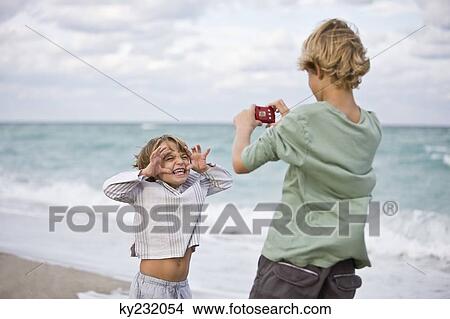 Boy taking his brother's picture with a digital camera View Large Photo Image Picture - Boy taking his brother's picture with a digital camera. Fotosearch