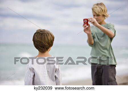 Boy taking his brother's picture with a digital camera View Large Photo Image Stock Photo - Boy taking his brother's picture with a digital camera. Fotosearch