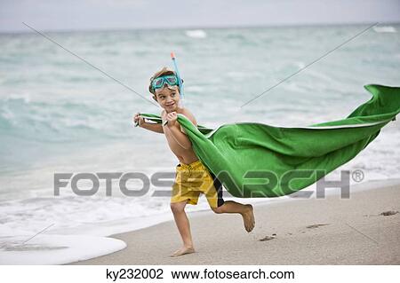Stock Image - Boy wearing a scuba mask and running on the beach. Fotosearch