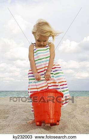 Girl holding a sand pail on the beach View Large Photo Image Stock Image - Girl holding a sand pail on the beach. Fotosearch
