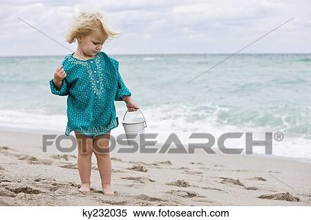 Girl holding a sand pail on the beach View Large Photo Image Stock Photography - Girl holding a sand pail on the beach. Fotosearch