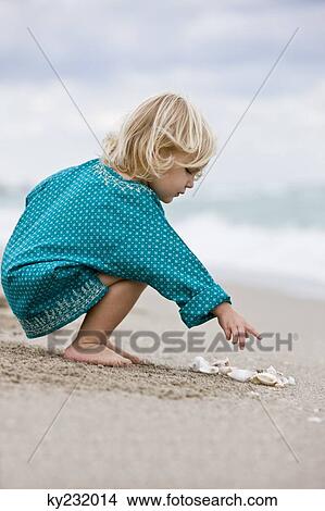 Girl playing with shells on the beach View Large Photo Image Picture - Girl playing with shells on the beach. Fotosearch
