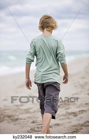 Rear view of a boy walking on the beach View Large Photo Image Stock Photo - Rear view of a boy walking on the beach. Fotosearch