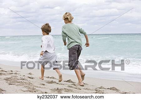 Rear view of two boys running on the beach View Large Photo Image Stock Photo - Rear view of two boys running on the beach. Fotosearch