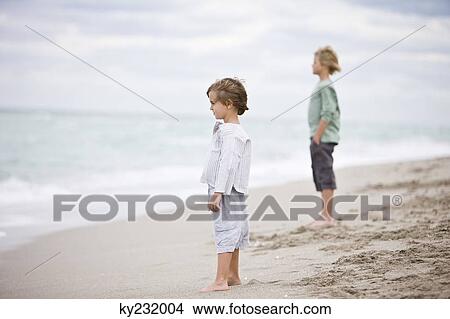 Two boys standing on the beach View Large Photo Image Picture - Two boys standing on the beach. Fotosearch