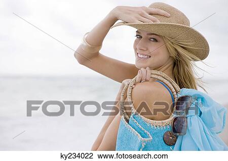 Stock Image - Woman carrying a bag on the beach. Fotosearch