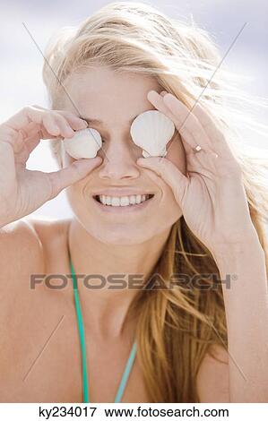 Woman holding shells in front of her eyes View Large Photo Image Stock Photo - Woman holding shells in front of her eyes. Fotosearch
