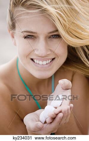 Stock Image - Woman holding shells on the beach. Fotosearch