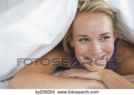 Close-up of a woman lying on the bed and smiling View Large Photo Image Picture - Close-up of a woman lying on the bed and smiling. Fotosearch