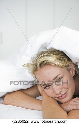 Close-up of a woman lying on the bed and smiling View Large Photo Image Stock Image - Close-up of a woman lying on the bed and smiling. Fotosearch
