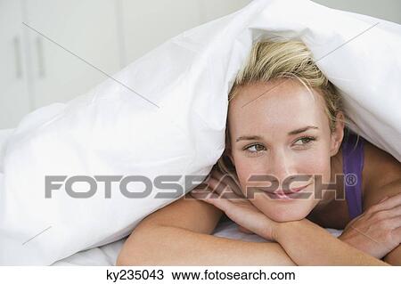 Close-up of a woman lying on the bed and smiling View Large Photo Image Stock Image - Close-up of a woman lying on the bed and smiling. Fotosearch