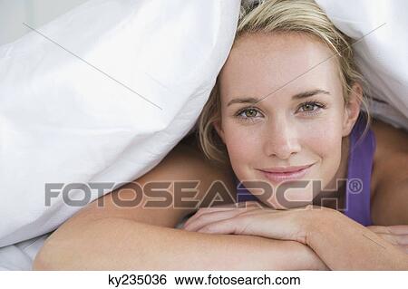 Close-up of a woman lying on the bed and smiling View Large Photo Image Stock Photograph - Close-up of a woman lying on the bed and smiling. Fotosearch