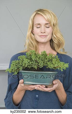 Woman holding a potted plant View Large Photo Image Stock Image - Woman holding a potted plant. Fotosearch