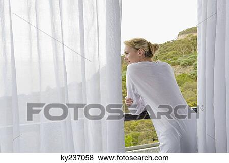 Rear view of a woman standing on balcony View Large Photo Image Stock Photo - Rear view of a woman standing on balcony. Fotosearch
