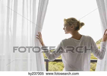 Rear view of a woman standing on balcony View Large Photo Image Stock Photography - Rear view of a woman standing on balcony. Fotosearch