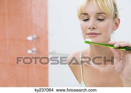 Reflection of a woman in the mirror holding a toothbrush View Large Photo Image Picture - Reflection of a woman in the mirror holding a toothbrush. Fotosearch